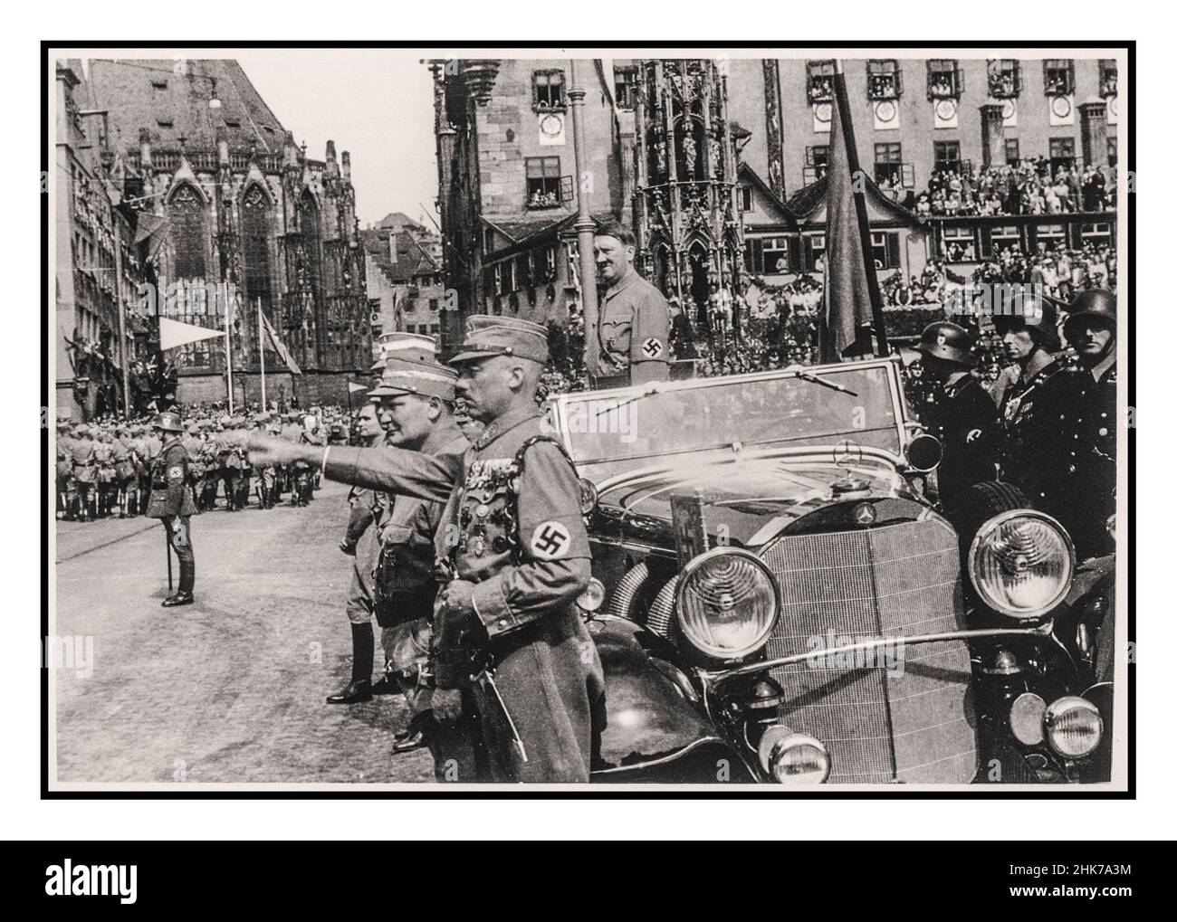 Adolf Hitler in piedi nella sua vettura Mercedes a cielo aperto al Rally di Norimberga 1935, Germania - SA Sturmabteilung truppe politiche della milizia nazista, marcia passato Adolf Hitler durante una sfilata in città. Adolf Hitler degli anni '30 indossa una fascia da braccio swastika in una parata militare, in piedi in una vettura aperta Mercedes con Heil Hitler salutano il passaggio delle truppe di Sturmabteilung Hermann Goring in primo piano Norimberga Germania Goring e Hess sono viste in primo piano Foto Stock
