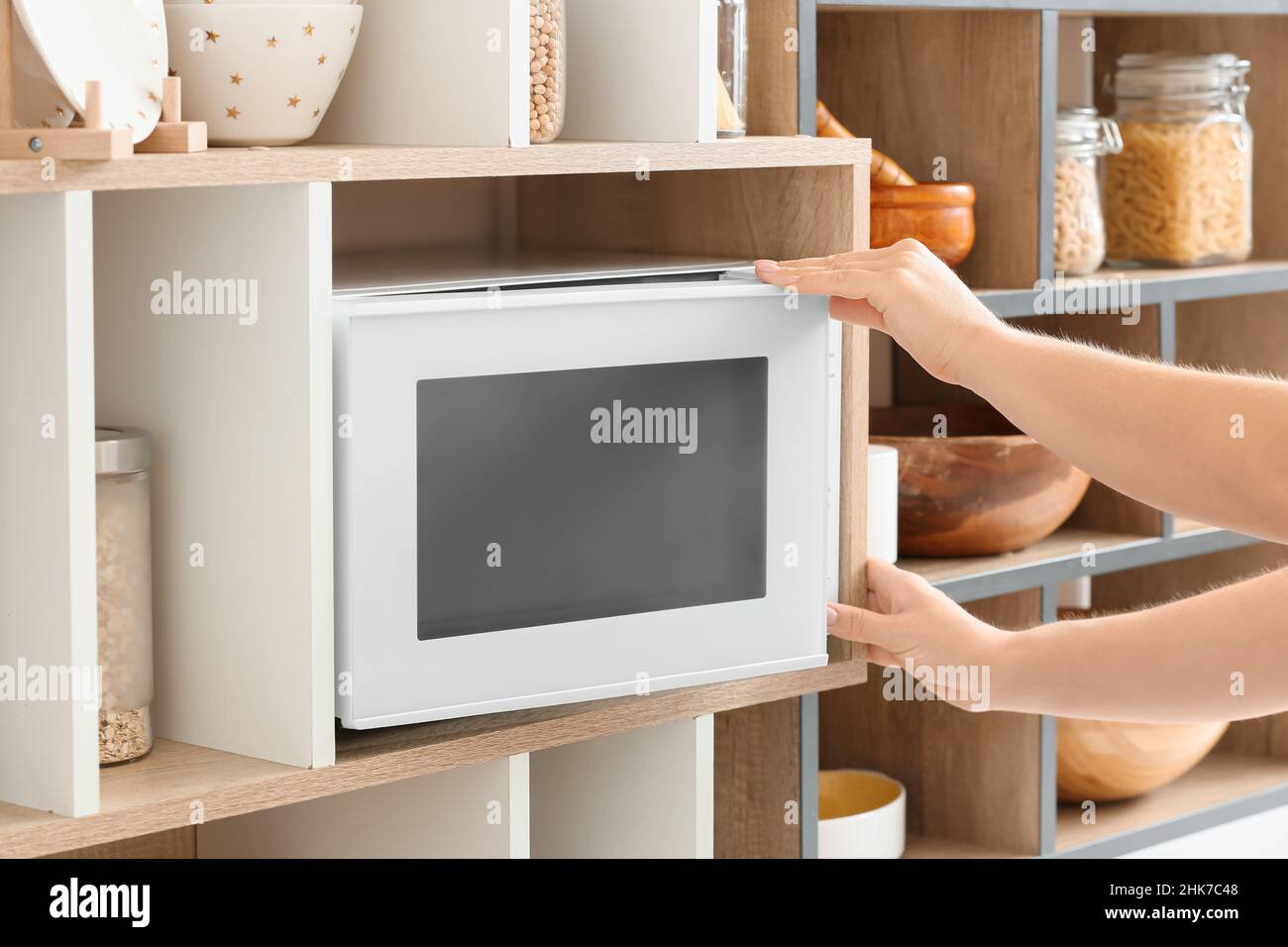 Giovane donna che apre forno a microonde su scaffale in cucina, primo piano  Foto stock - Alamy