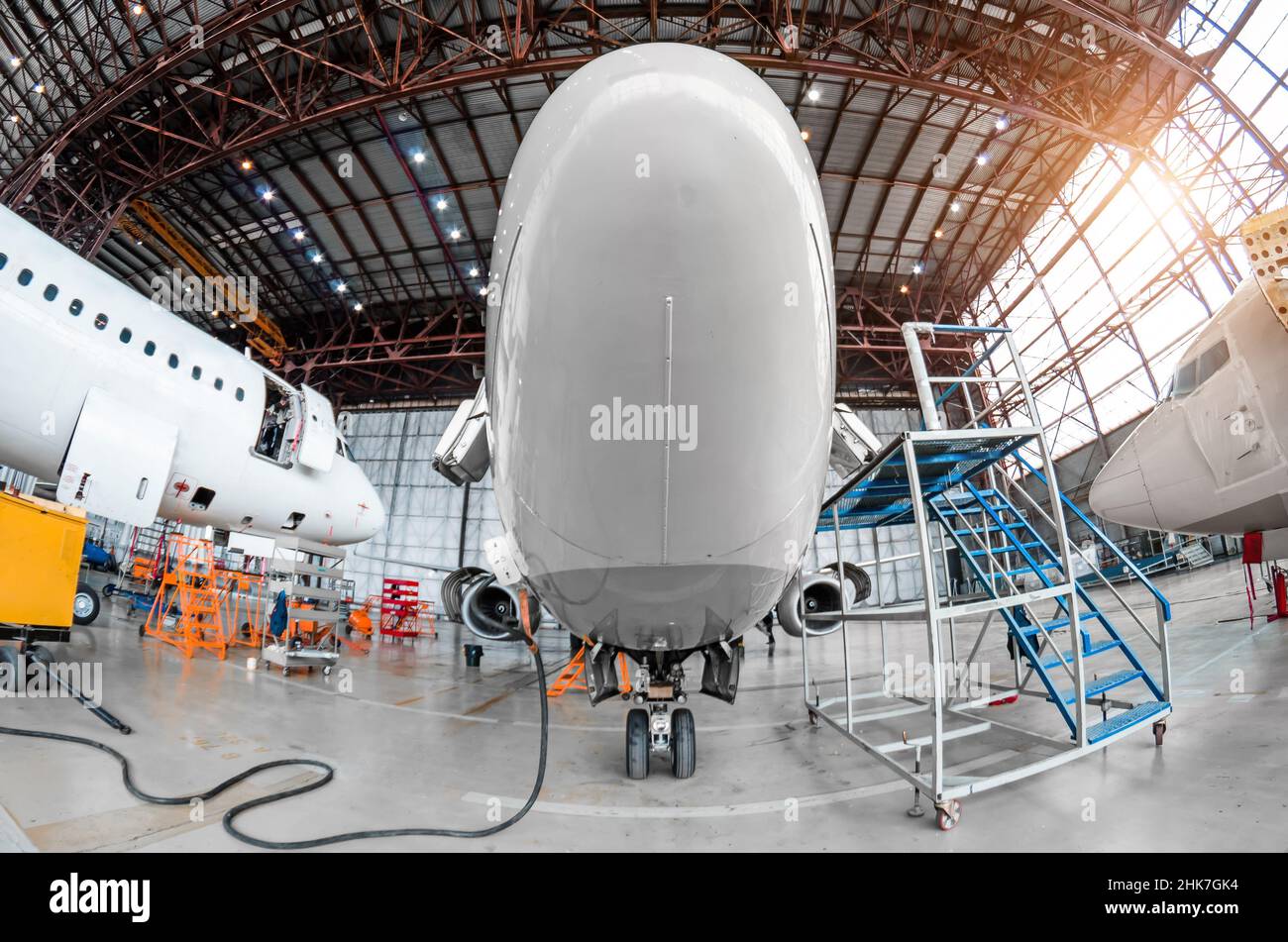 Hangar aereo con velivolo, primo piano di atterraggio anteriore del velivolo di atterraggio in riparazione di manutenzione Foto Stock Hangar aereo con velivolo, primo piano di atterraggio anteriore del velivolo di atterraggio in riparazione di manutenzione Foto Stock