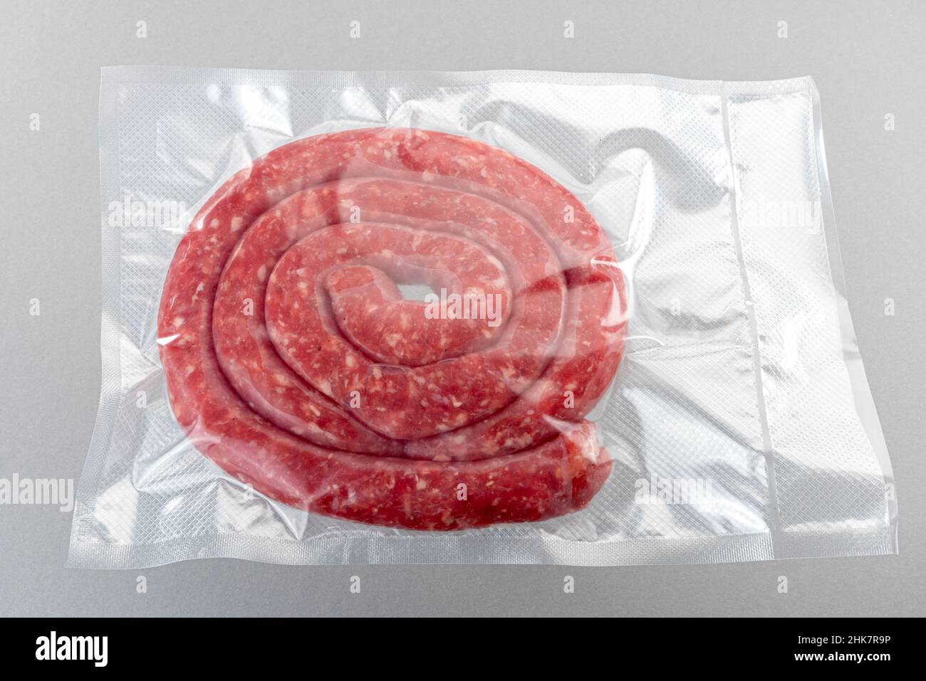 Salsiccia italiana (salsiccia) confezionata sottovuoto sigillata per la cottura sous vide isolata su sfondo grigio in vista dall'alto Foto Stock