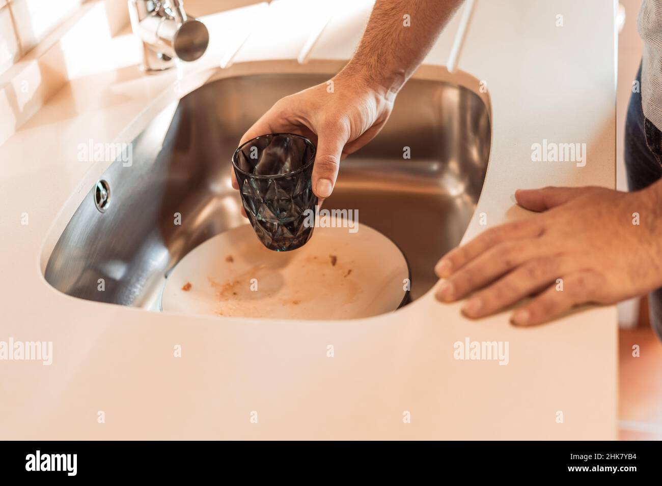 l'uomo irriconoscibile mette il vetro sporco nel lavandino Foto Stock