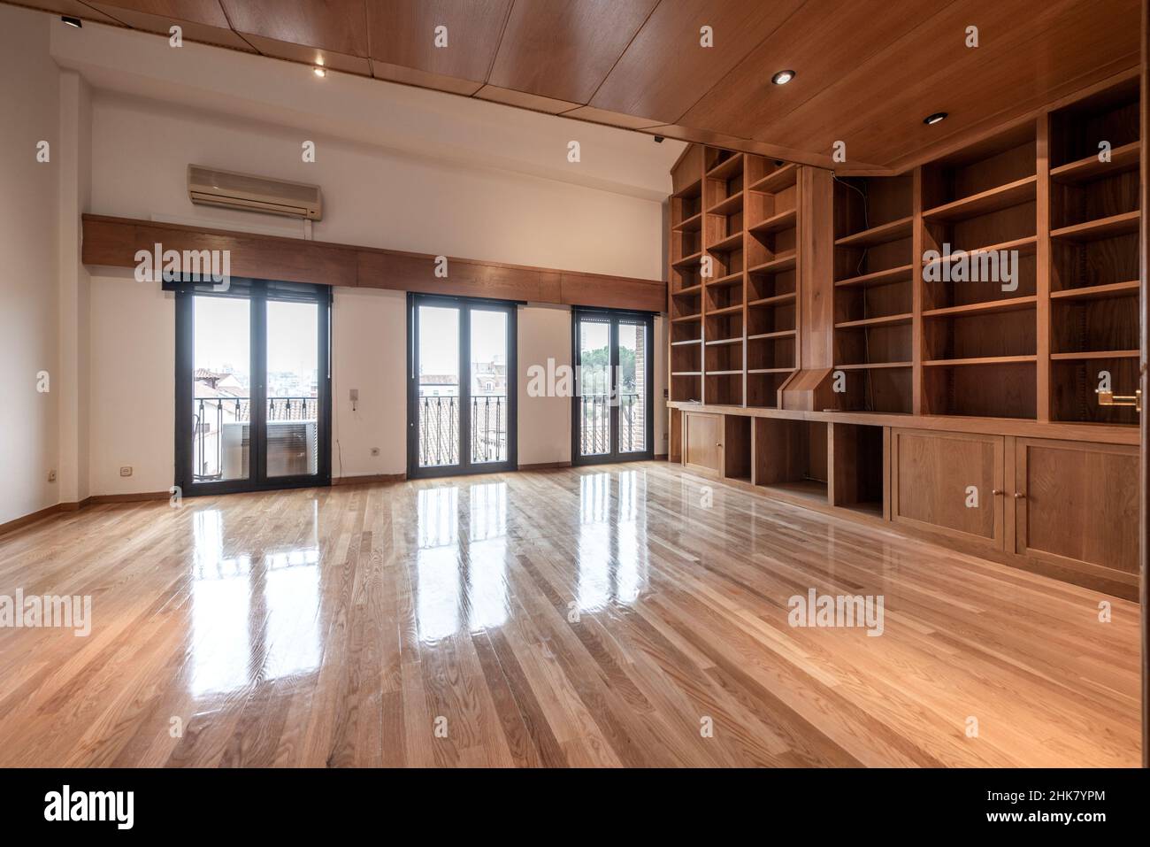 Soggiorno vuoto con grande libreria in rovere e pavimento in legno con lunghe tavole di rovere francese verniciato Foto Stock