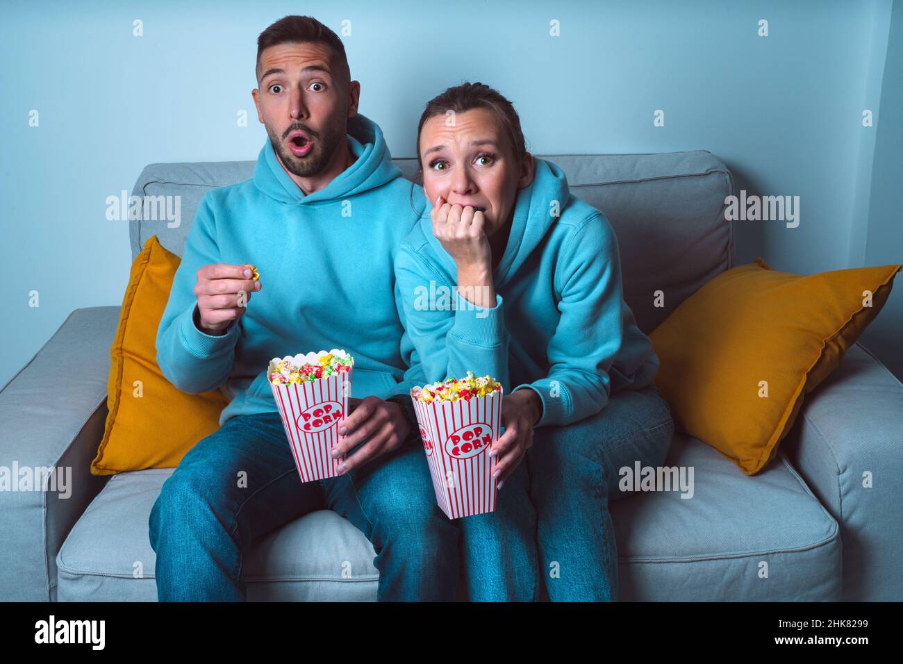 Giovane coppia con popcorn che guarda orrore o film spaventoso a casa Foto Stock