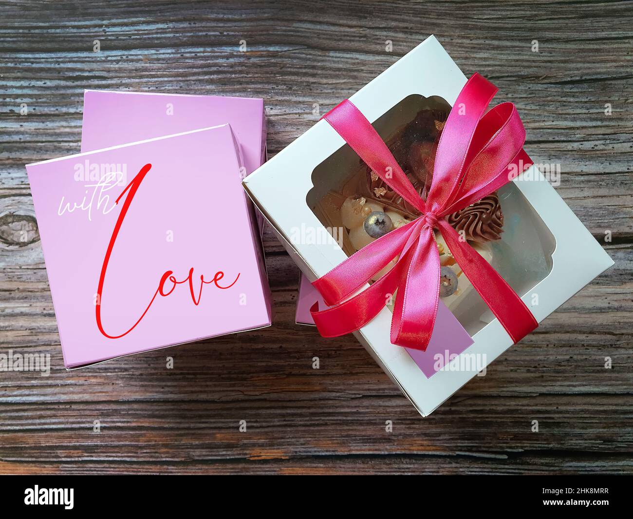 Vista dall'alto Vibrant Colour of Freshness Cake nella scatola di carta bianca e rosa con sfondo di legno San Valentino amore presente con amore Foto Stock