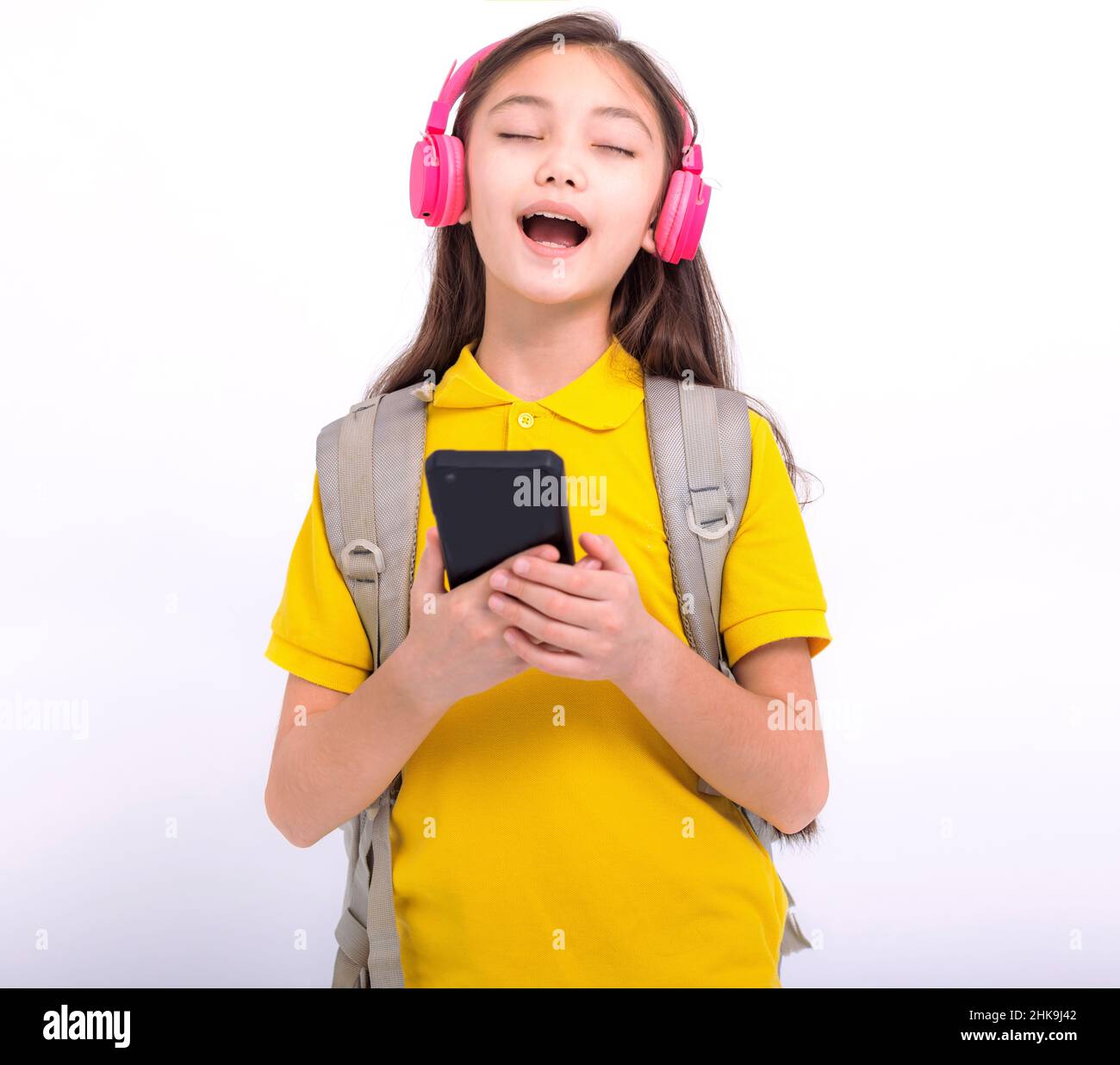 Ragazza felice studente ascoltare musica con cuffie e cantare canzone Foto Stock