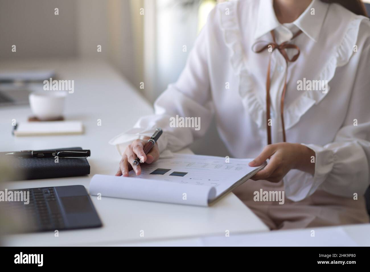 Immagine ritagliata, assistente finanziario femminile che compila il rapporto di forma finanziaria al suo tavolo. Foto Stock