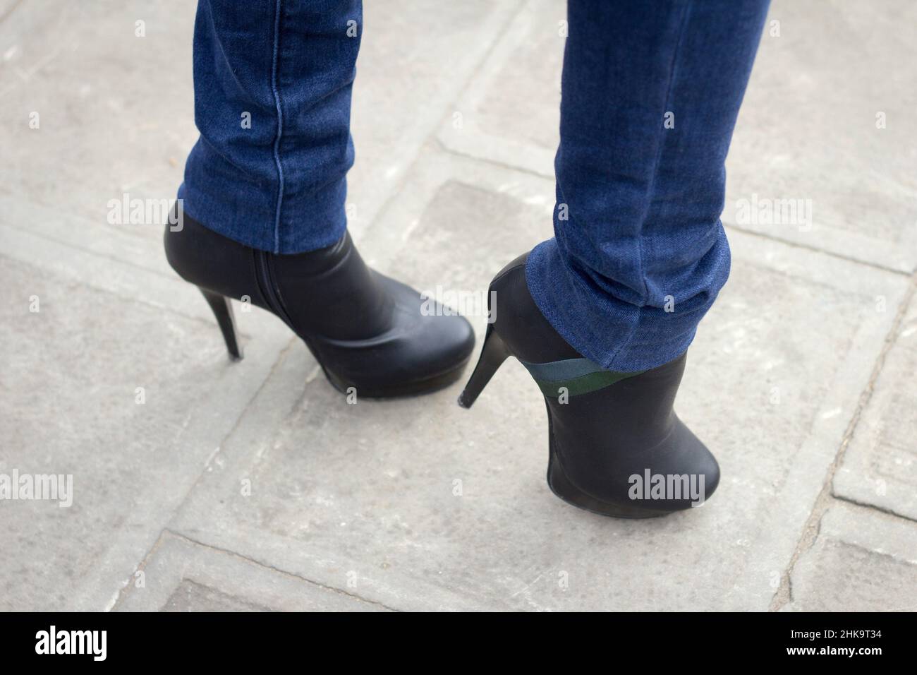 Gamba ragazza con stivali neri su un tacco alto. Stile Street Foto Stock