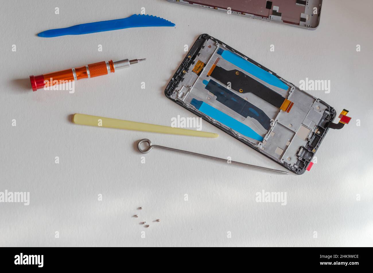 Concetto di riparazione degli smartphone. Utensile manuale e telefono smontato poggiato sul tavolo. Parte di una serie. All'interno. Messa a fuoco selettiva. Foto Stock
