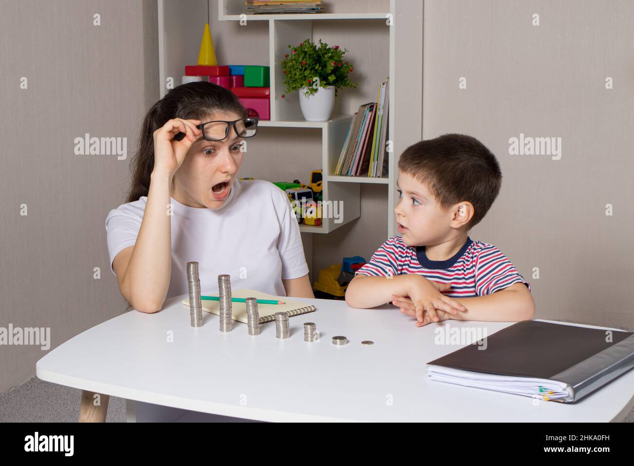 Il genitore insegna al bambino come maneggiare i soldi. Corso di alfabetizzazione finanziaria per bambini in età prescolare e scolastica. Foto Stock