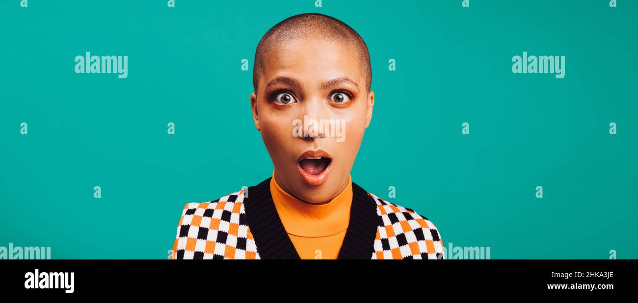 Donna che guarda scioccato in uno studio. Giovane donna alla moda che guarda la macchina fotografica con gli occhi e la bocca spalancata. Donna hipster con un anello del setto s Foto Stock