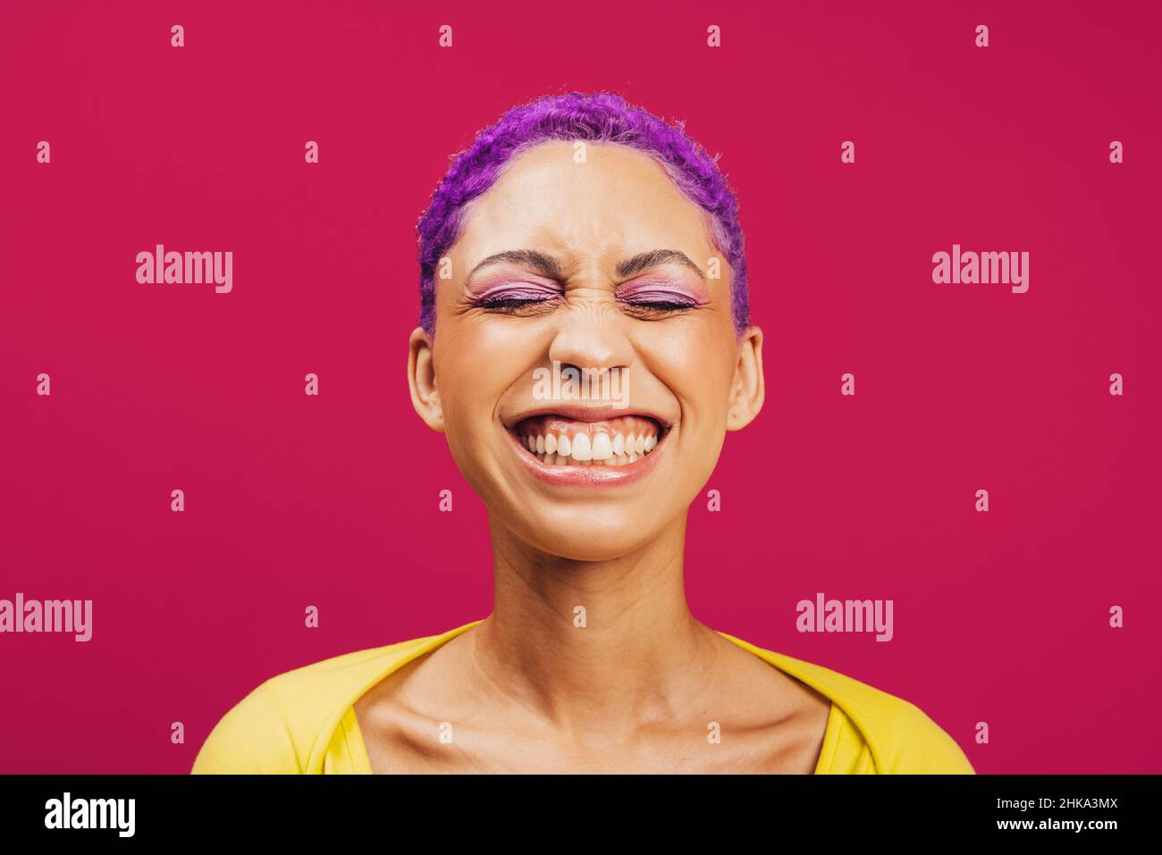 Vibrazioni vibranti. Giovane donna eccitata sorridendo con gli occhi chiusi mentre si alza su uno sfondo rosa. Giovane donna alla moda che indossa il trucco con Foto Stock