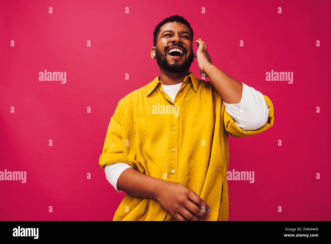 Ascoltare la mia playlist preferita. Un giovane sorridente allegro mentre ascolti la musica utilizzando le cuffie wireless in uno studio. Spensierate il giovane uomo s Foto Stock