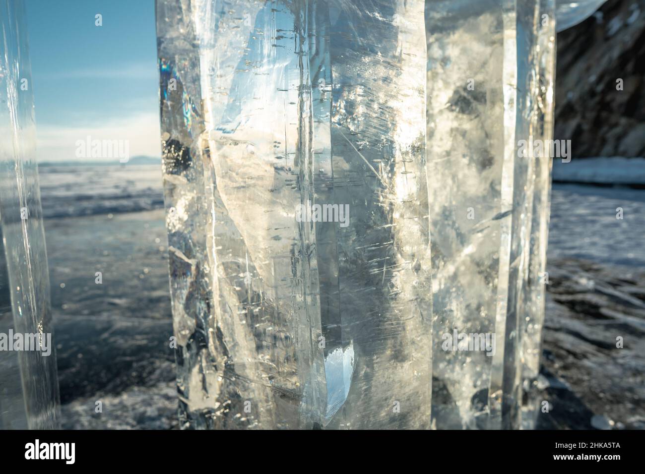 Un grande blocco trasparente di ghiaccio con crepe nei raggi del sole al tramonto. Bella inverno naturale astrazione di ghiaccio Baikal Foto Stock