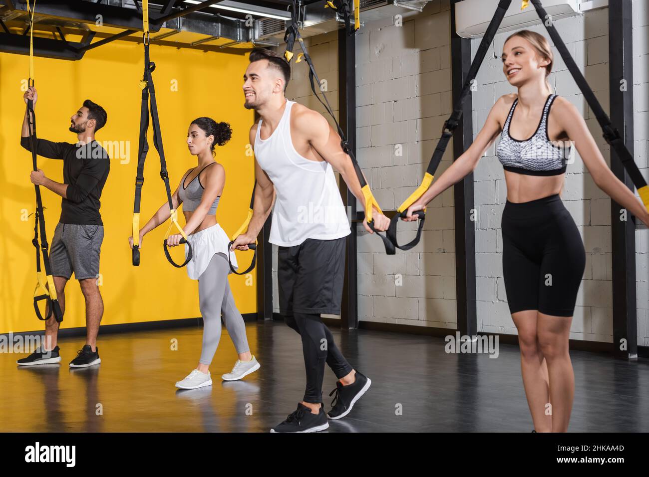 Formazione positiva di persone interrazziali con cinghie di sospensione in palestra Foto Stock