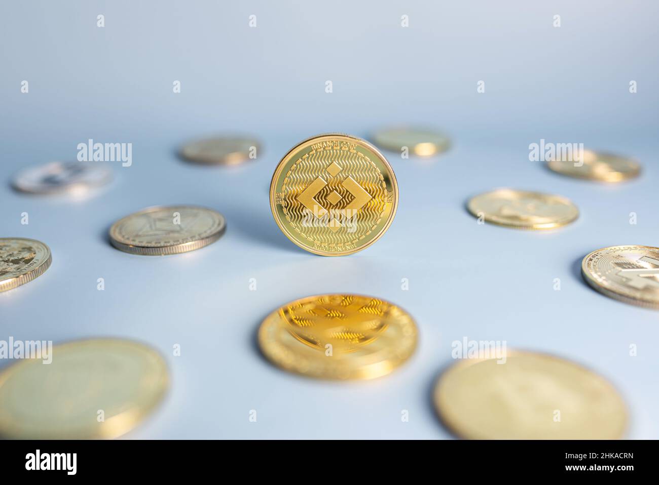 Moneta di Binance in piedi centrale posto tra un mazzo di monete criptovaluta su sfondo blu. Banner con cripto dorato BNB gettone. Primo piano, messa a fuoco morbida. Foto Stock