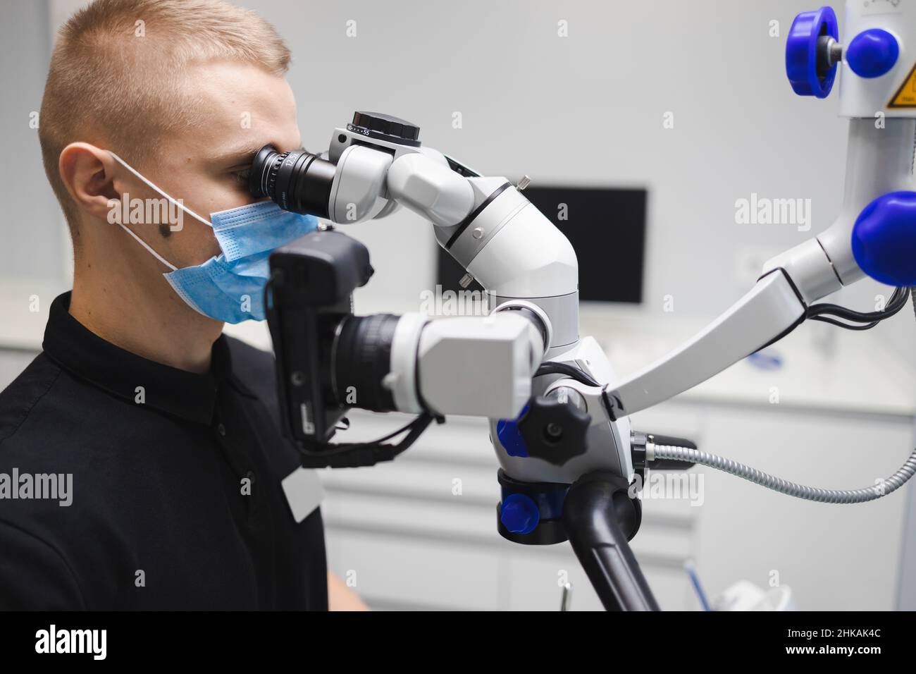 Medico dentista maschile che utilizza il microscopio per il trattamento dentale Foto Stock