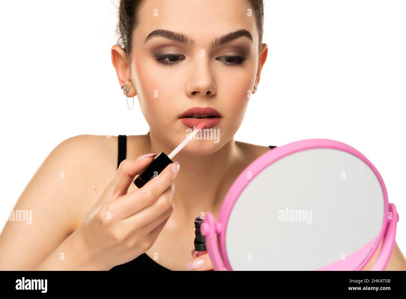 bella ragazza teen applyes labbro gloss su sfondo bianco Foto Stock