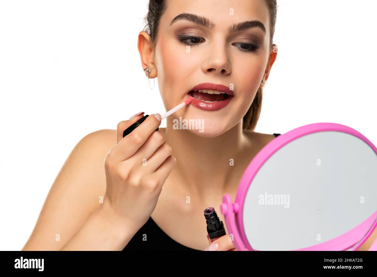 bella ragazza teen applyes labbro gloss su sfondo bianco Foto Stock