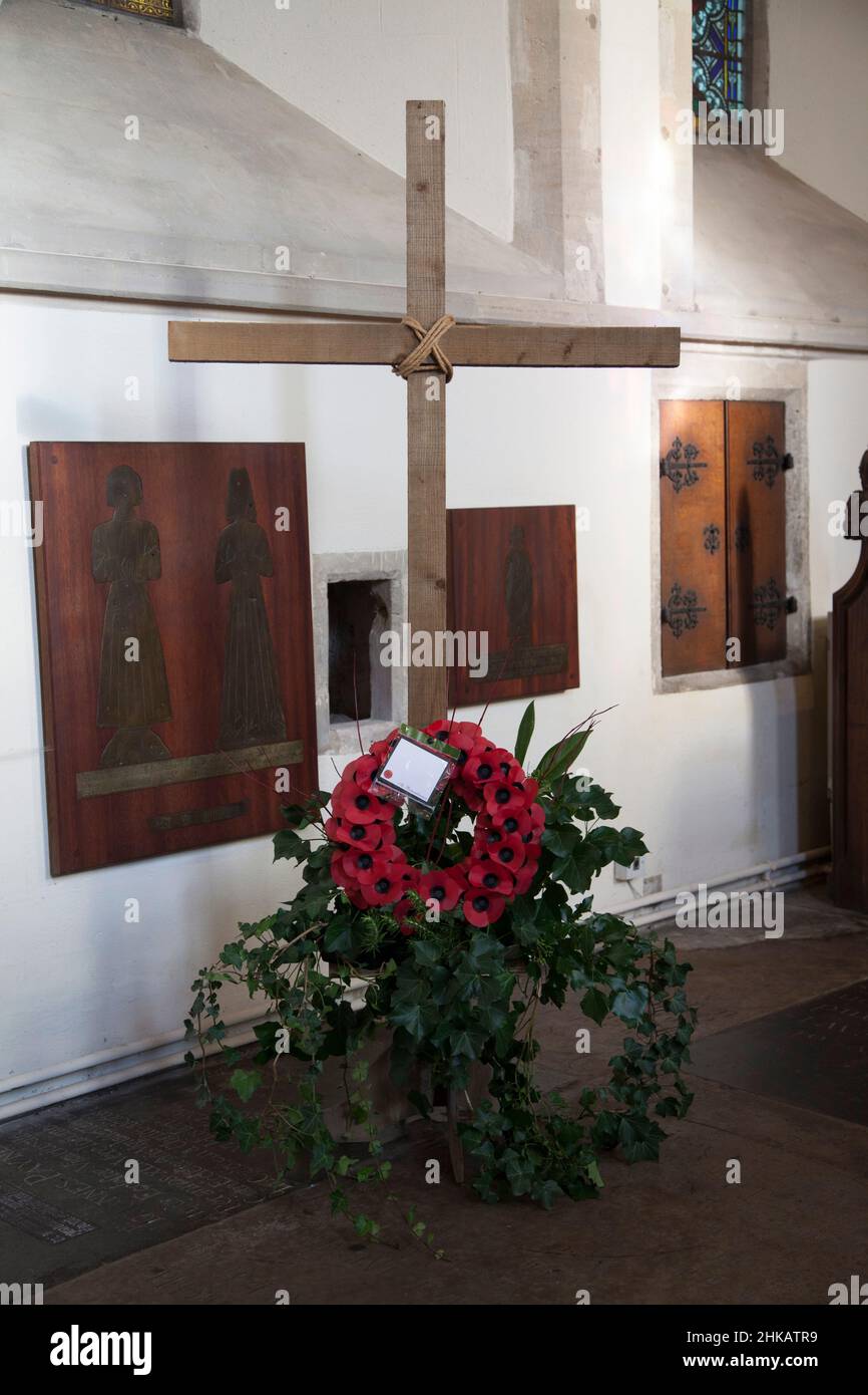 Una semplice croce in legno, decorata con edera e una corona rossa di papavero, per il giorno della memoria Foto Stock