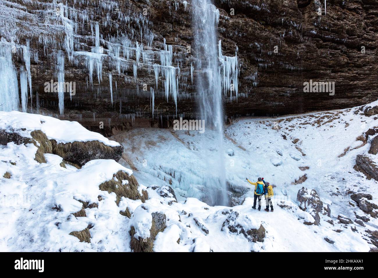 FMother e figlio si trovano di fronte alla cascata ghiacciata della cascata Pericnik in inverno, nel Parco Nazionale del Triglav, Slovenia Foto Stock