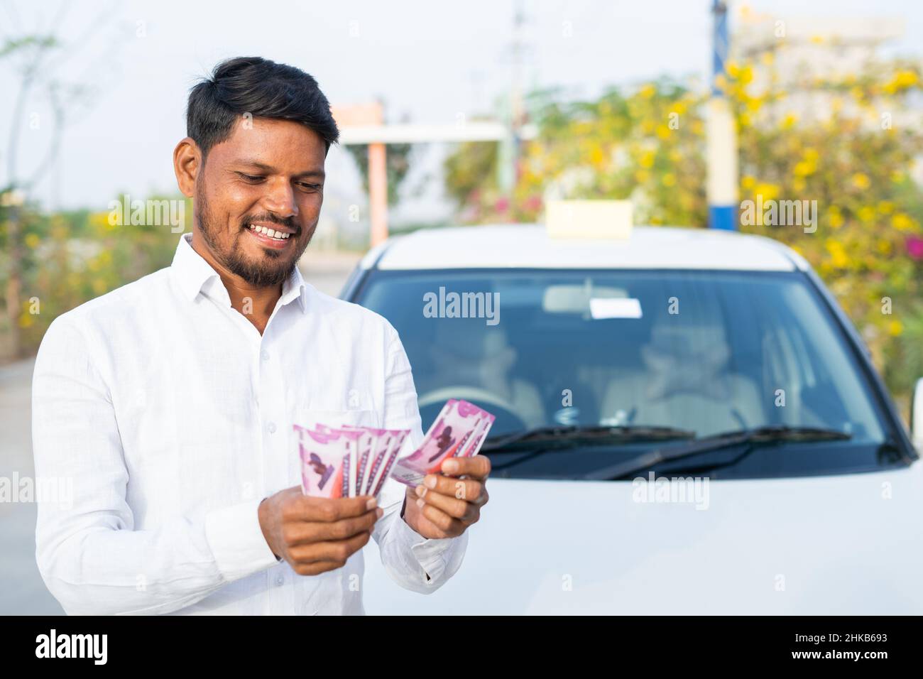 Felice sorridente conducente di taxi contare soldi di fronte all'auto - concetto di business profit, approvazione prestito, finanziario, bancario e di lavoro autonomo. Foto Stock