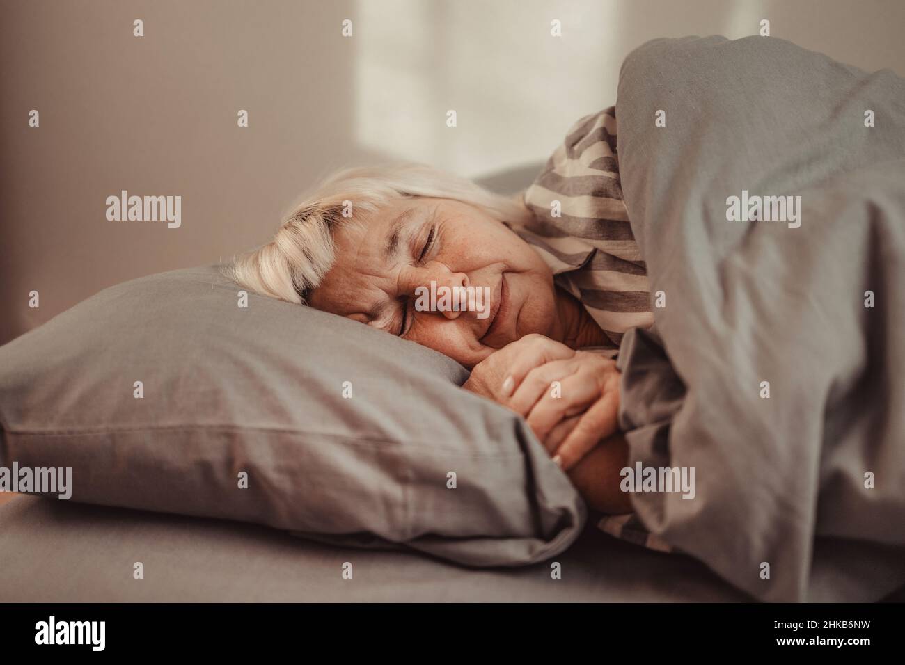 Sogni dolci. Bella 50s donna che dormiva a letto presto al mattino. Persone, relax e comfort Foto Stock