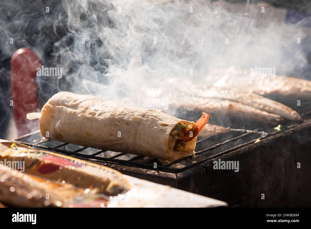 Produzione di Balik Ekmek sul fuoco di legno a Istanbul, Turchia, un tradizionale cibo turco di strada fatto di sgombro alla griglia avvolto con verdure nel pane Foto Stock