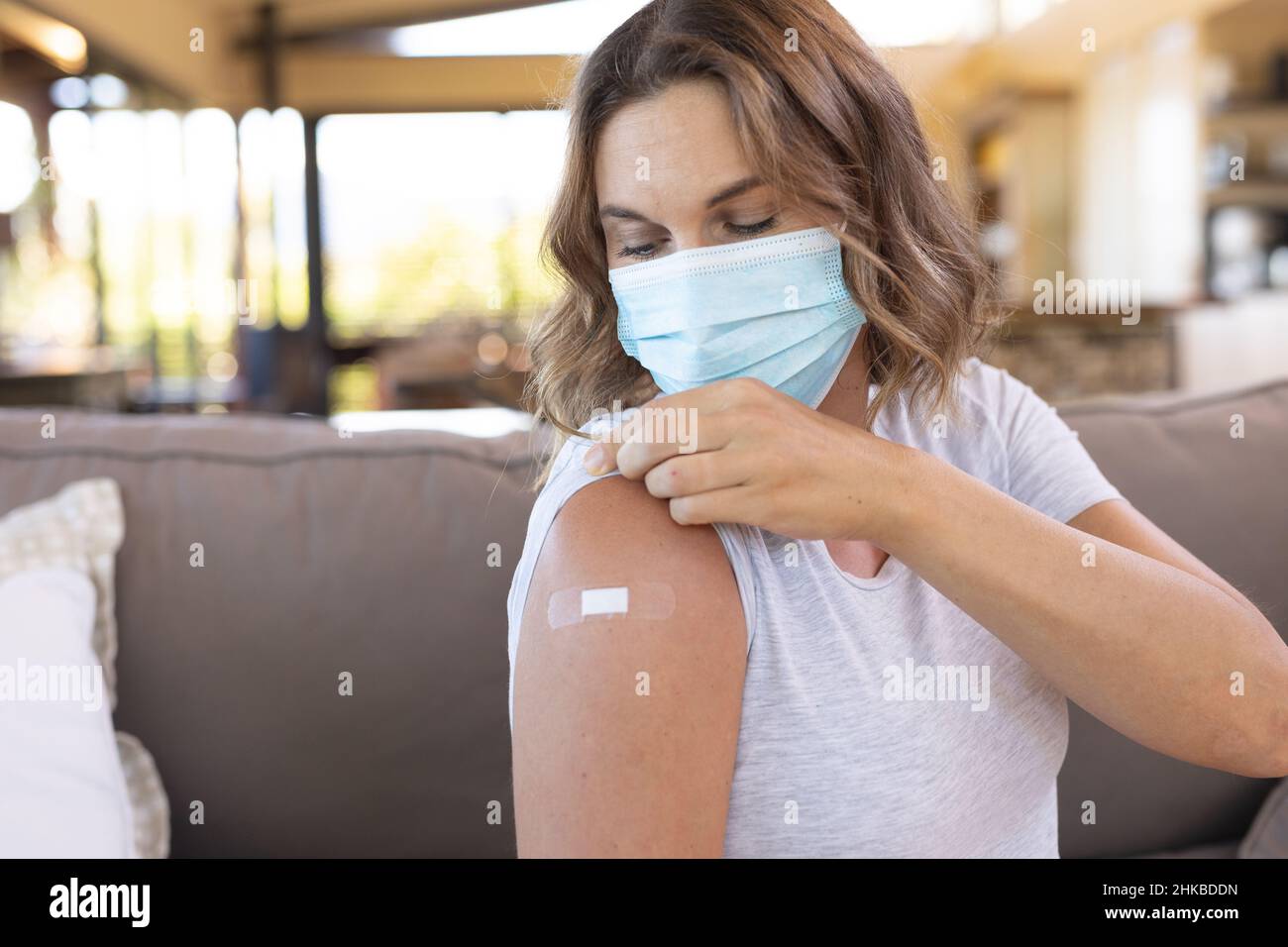 Donna incinta caucasica che indossa una maschera facciale che mostra la spalla dopo aver ricevuto il vaccino Foto Stock