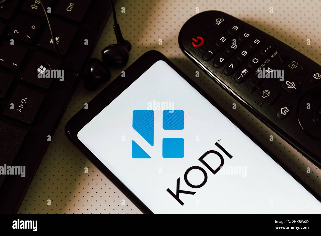 In questa foto, il logo del Kodi Entertainment Center, un software  multimediale gratuito e open source visualizzato su uno smartphone accanto  a un telecomando TV, auricolari e una tastiera. (Foto di Rafael