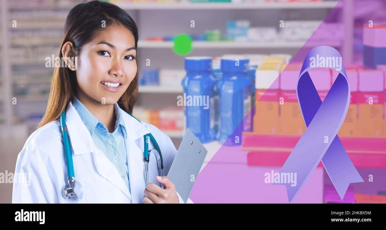 Immagine composita di nastro blu e sorridente medico asiatico giovane in piedi in farmacia ospedale Foto Stock