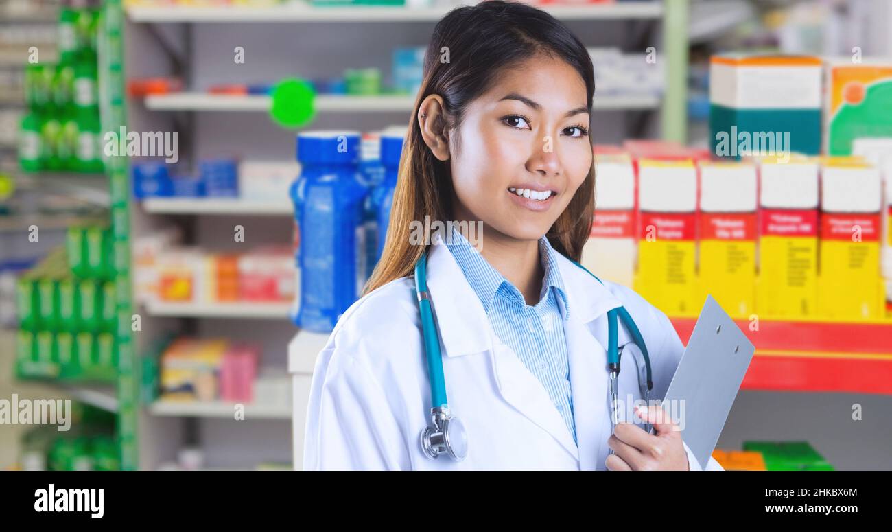 Sorridente medico asiatico giovane donna tenendo appunti mentre in piedi in farmacia ospedale Foto Stock