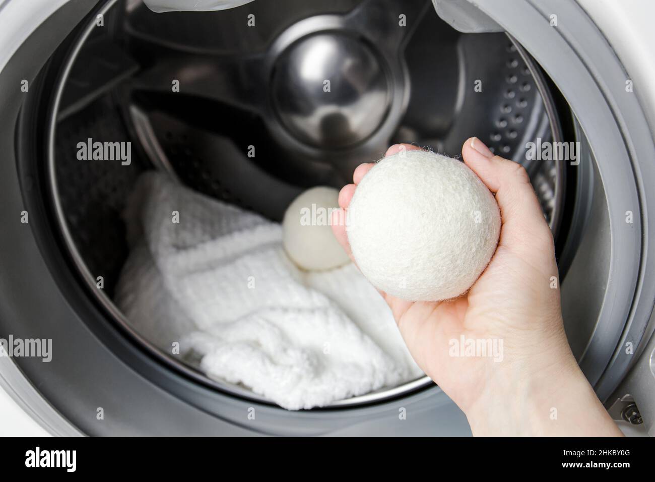 Donna che usa palle di lana asciugatrice per vestiti più morbidi mentre  asciuga in lavatrice concetto. Scaricare l'elettricità statica e abbreviare  l'asciugatura Foto stock - Alamy