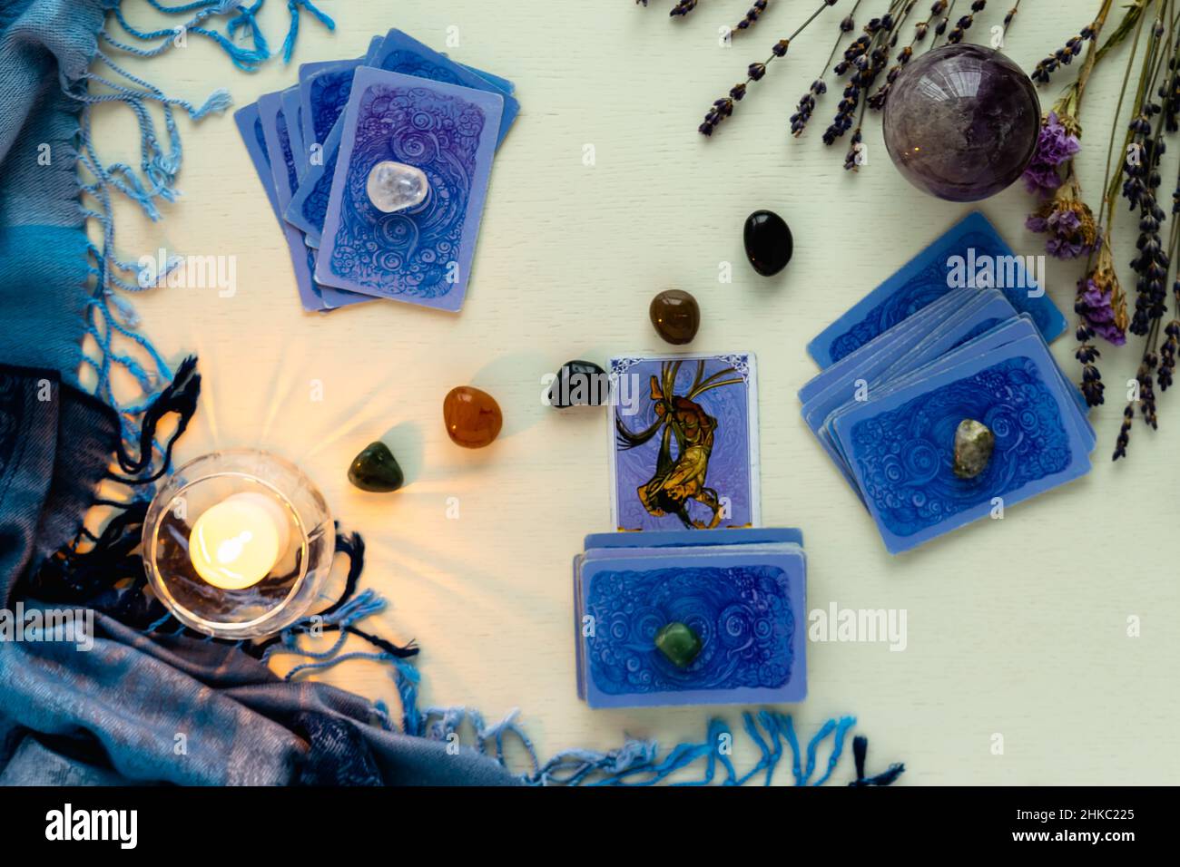 Minsk, Bielorussia - Febbraio 2022: Una scheda di un uomo impiccato in divinazione Tarocchi con candele e pietre su un tavolo luminoso con fiori secchi e una tovaglietta blu Foto Stock