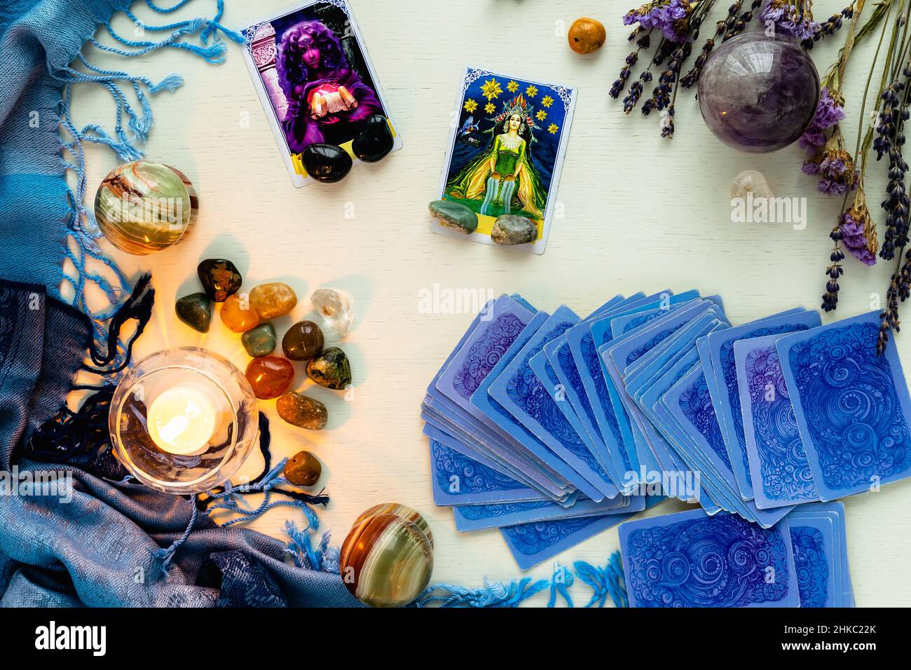 Minsk, Bielorussia - Febbraio 2022: Carte star e priestess in divinazione tarocchi con candele e pietre su un tavolo luminoso con fiori secchi e un ta blu Foto Stock