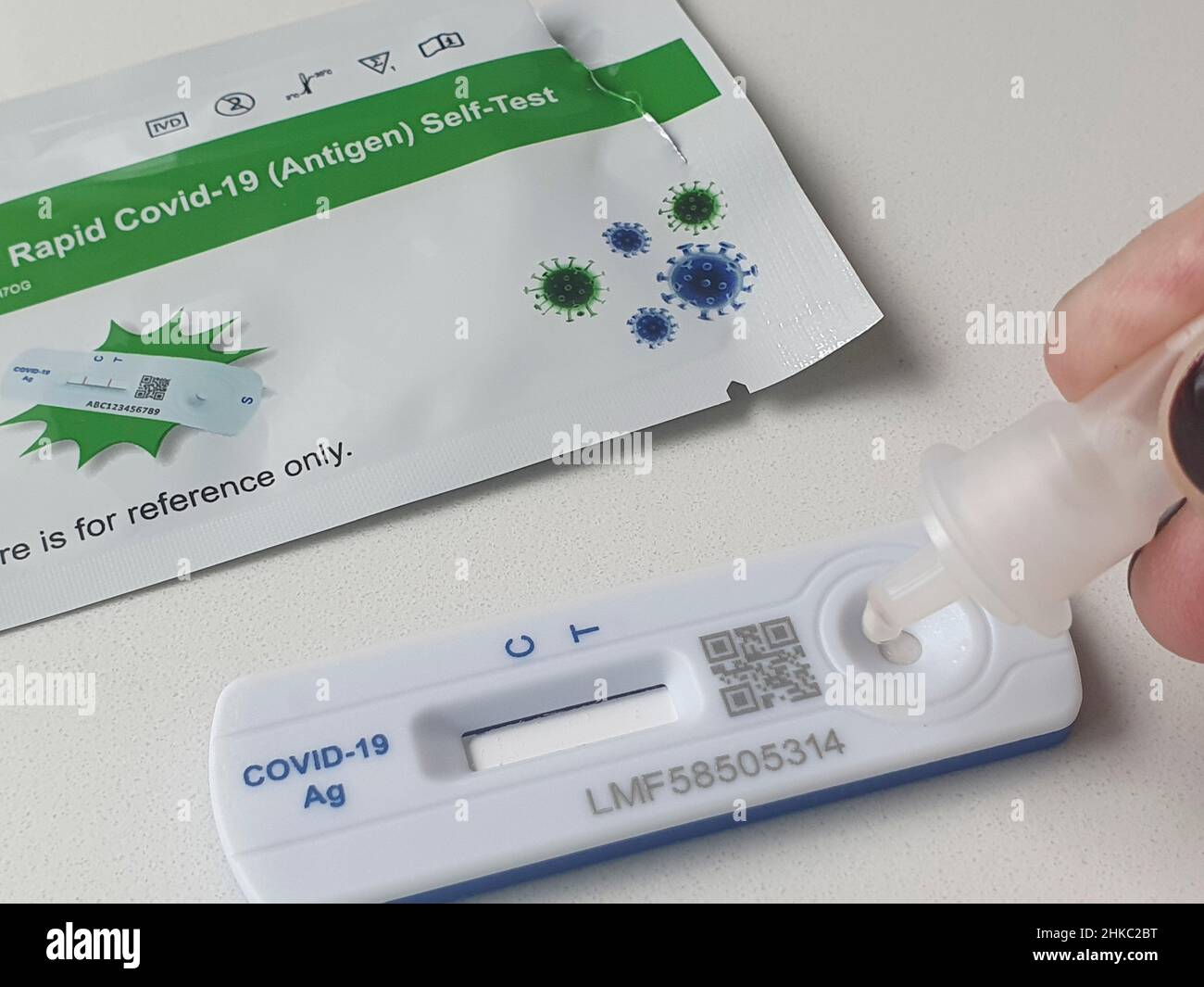 Londra, UK, 3 febbraio 2022: Una persona pone quattro gocce di soluzione tampone contenente materiale da un tampone nasale sulla cassetta di prova di un kit per test a flusso laterale. I test rapidi dell'antigene vengono ora utilizzati senza test PCR di follow-up. Questo test viene eseguito a Clapham, Londra, dove i tassi di infezione del covid stanno aumentando di nuovo per il distretto di Lambeth. Anna Watson/Alamy Live News Foto Stock