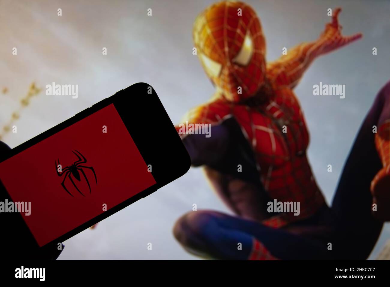 Rheinbach, Germania 15 ottobre 2021, il logo Spiderman sul display di uno smartphone di fronte a una scena di un film Spiderman in TV Foto Stock