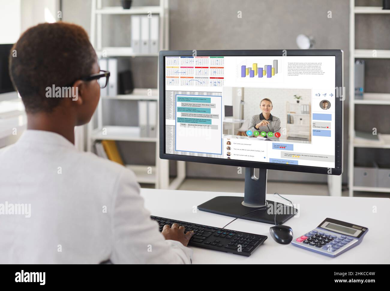 Donna che lavora sul computer dell'ufficio e comunica in chat di lavoro e tramite videochiamate Foto Stock