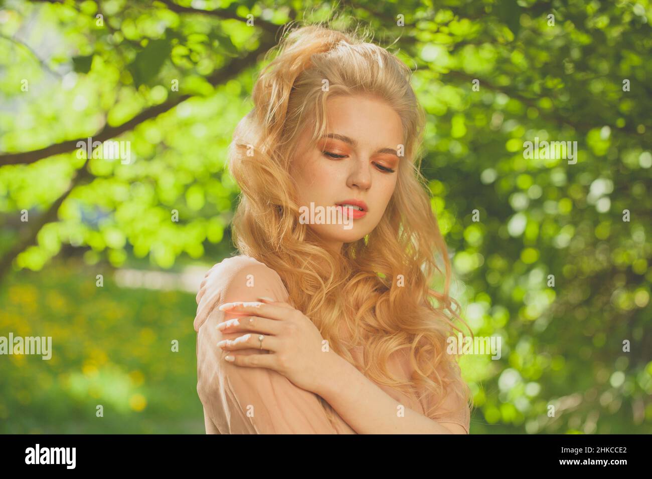 Ritratto di una bella giovane donna in piedi tra la natura nel parco alla luce del sole Foto Stock