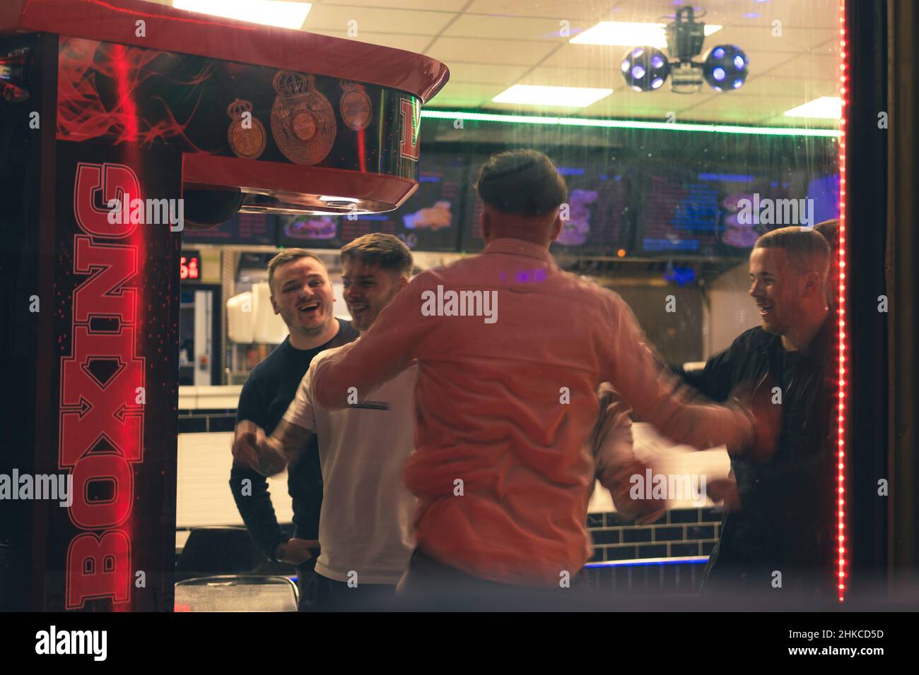 Gli uomini celebrano il successo del gioco arcade di pugilato in un takeaway, come parte di una serata fuori a Newcastle upon Tyne, Regno Unito. Foto Stock