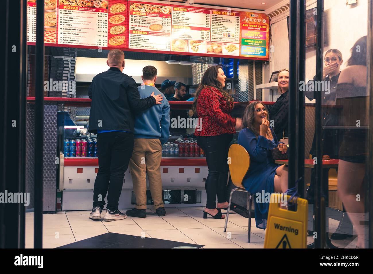 Persone che ordinano e attendono cibo a un takeaway come parte di una serata fuori a Newcastle upon Tyne, Regno Unito. Foto Stock