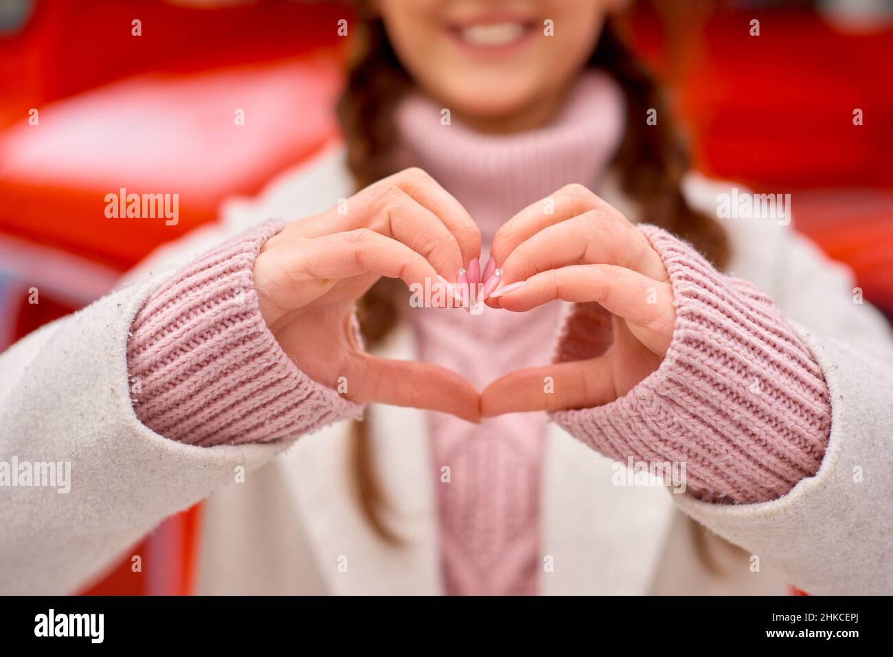 Il concetto di giorno di San Valentino. Amore nell'aria. La donna sorride e tiene le mani in forma di cuore per gratitudine. Foto Stock
