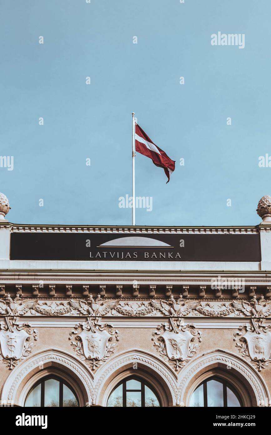 Frammento di edificio della Banca di Lettonia con la bandiera di Lettonia sopra la targhetta del nome. Foto Stock