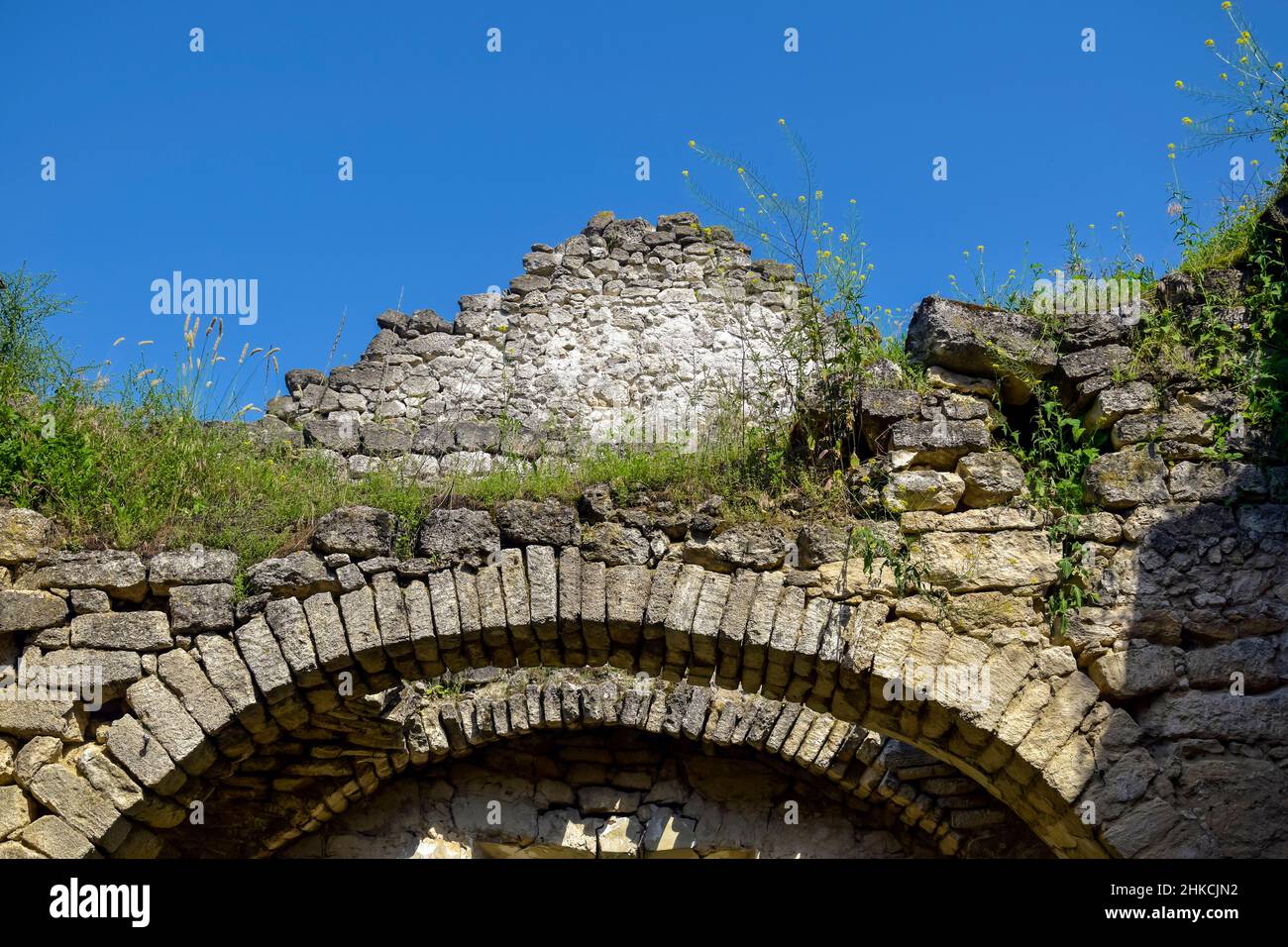 Rovine di un antico tempio cristiano contro il cielo blu. Soffitto crollato. Muratura, sala con volte ad arco. L'erba cresce sulle pareti. Rashkov, Moldavia. Cl Foto Stock