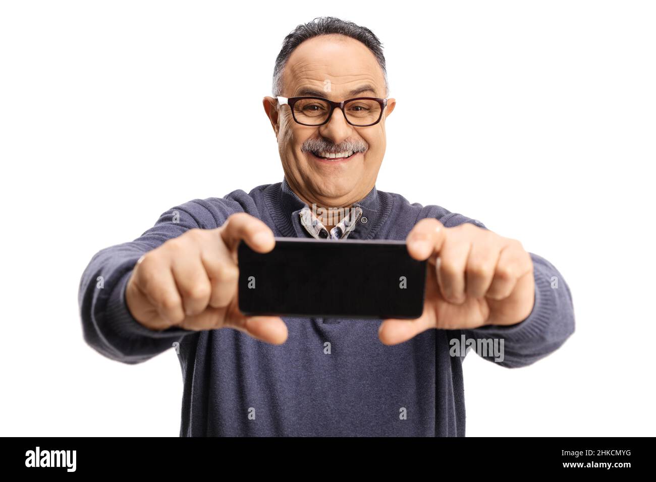 Uomo maturo sorridente che prende un selfie con uno smartphone isolato su sfondo bianco Foto Stock