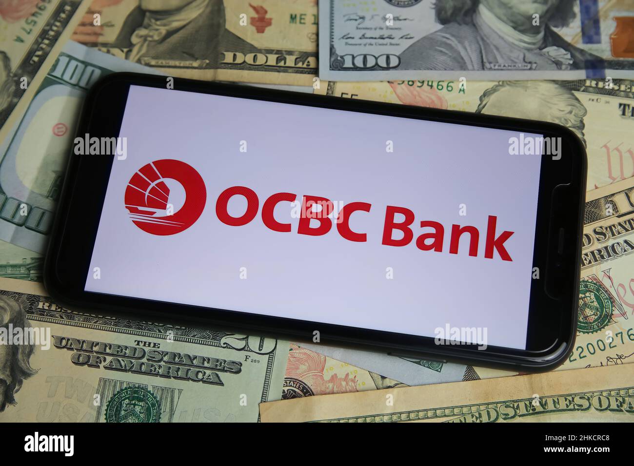 Viersen, Germania - Gennaio 9. 2022: Primo piano del telefono cellulare con il logo di ocbc bancario cinese ocbc, banconote in dollari USA sfondo Foto Stock