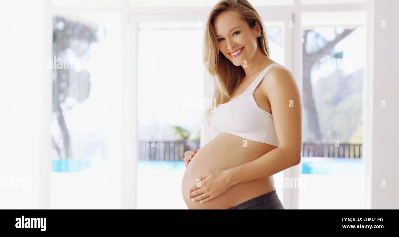 Il piccolo viene per primo. Ritratto corto di una giovane donna incinta attraente strofinando il suo bump del bambino. Foto Stock