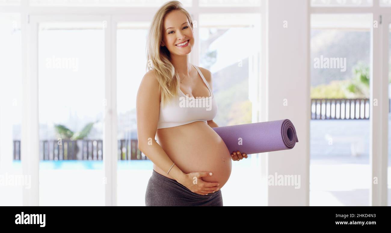 Im che si sta allenando per due. Ritratto corto di una giovane donna incinta attraente che porta un tappeto yoga. Foto Stock