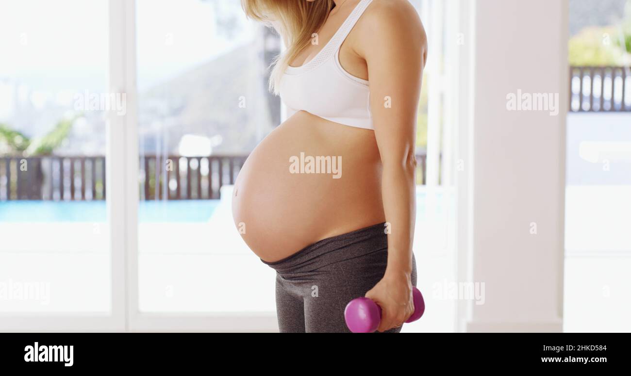 Mamma forte = bimbo forte. Scatto corto di una giovane donna incinta irriconoscibile che lavora fuori con i dumbbells. Foto Stock