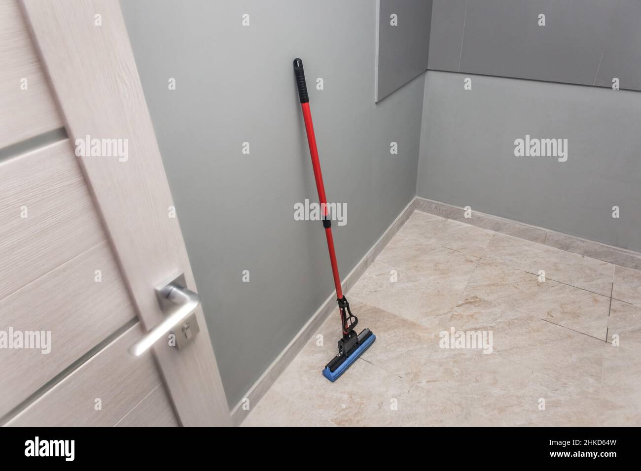 Il mop è appoggiato contro la parete e la pulizia del pavimento degli impianti di produzione. I lavori domestici e l'igiene delle strutture sanitarie. Foto Stock