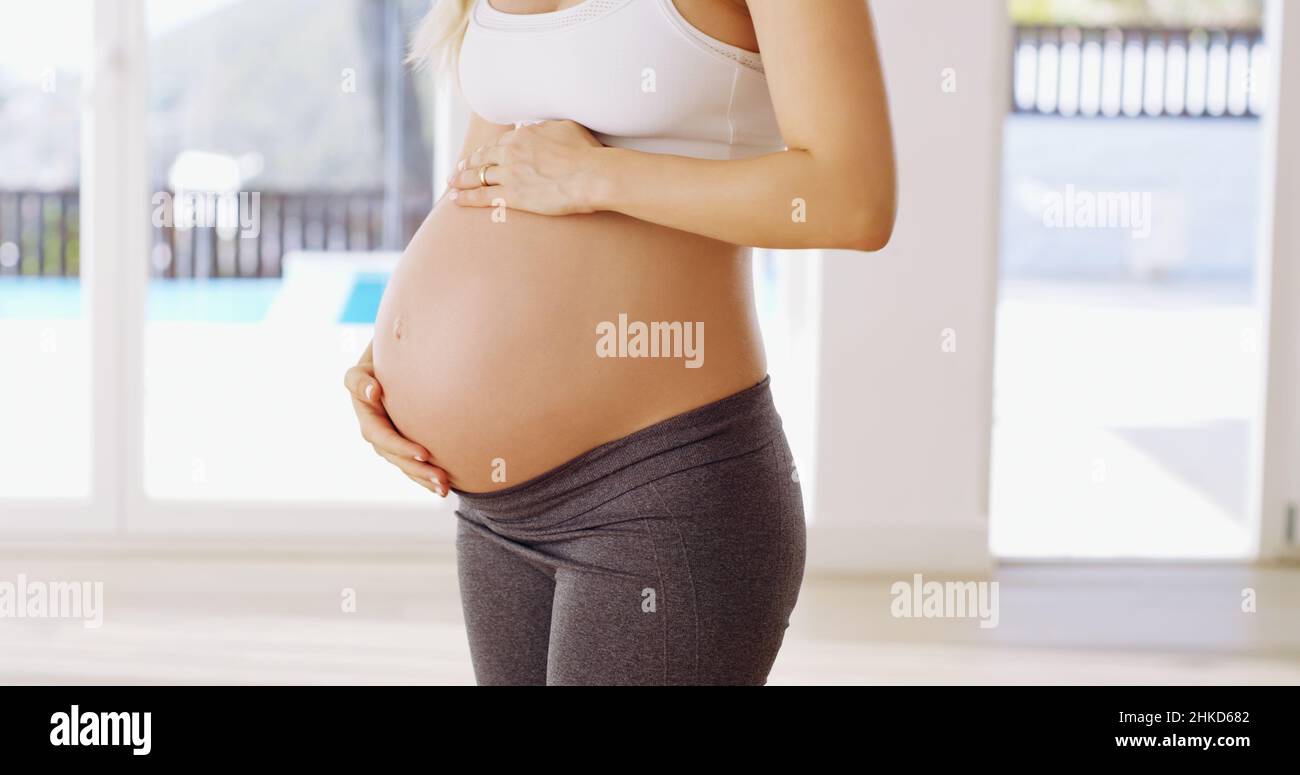 Il bambino viene prima. Scatto corto di una giovane donna incinta irriconoscibile strofinando il suo bump del bambino. Foto Stock